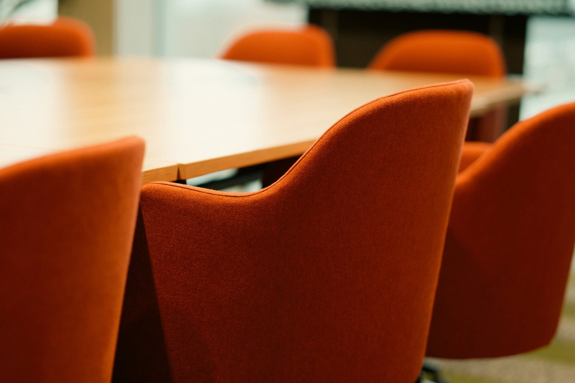 Conference meeting table seating interior with upholstered chairs around wooden table